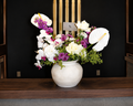 Moonlit Garden arrangement by Lenorah & Co. — ivory garden roses, white anthurium and cascading phalaenopsis orchids with violet stock in a hand-textured plaster vessel.