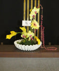 Statement Ikebana arrangement by Lenorah & Co. — orchids, protea and sculptural branch work composed on a kenzan pin frog in a designer vessel.